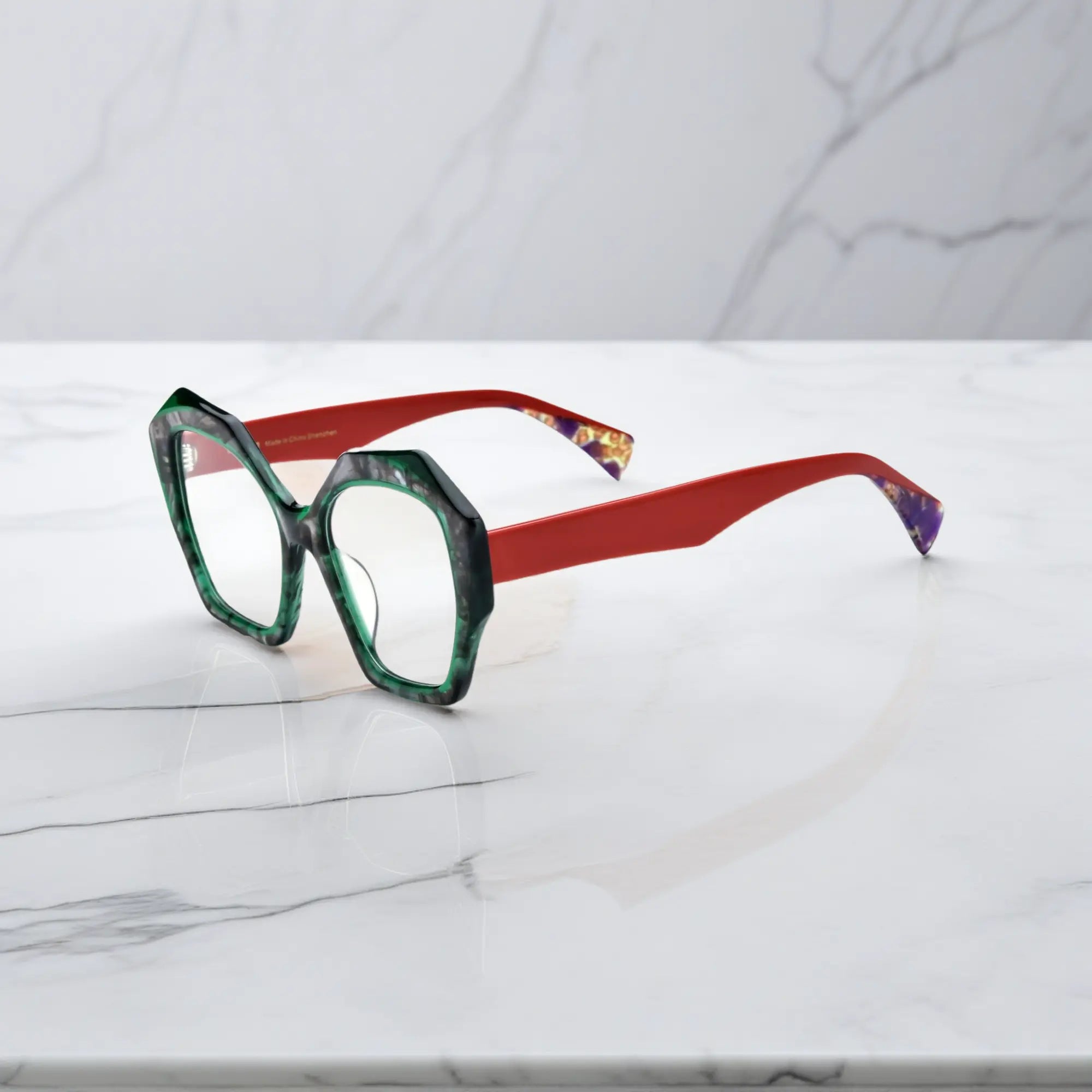 Side view showing sharp red acetate temples and geometric green marble frame of Crimson Jade glasses.